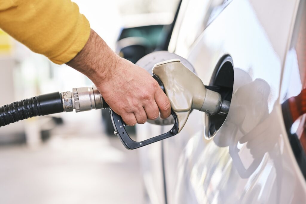 Pumping gas at gas pump. Closeup of man pumping gasoline fuel in car at gas station.