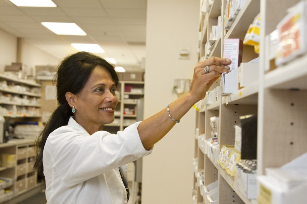 A female pharmacist is selecting a drug from the pharmacy inventory.